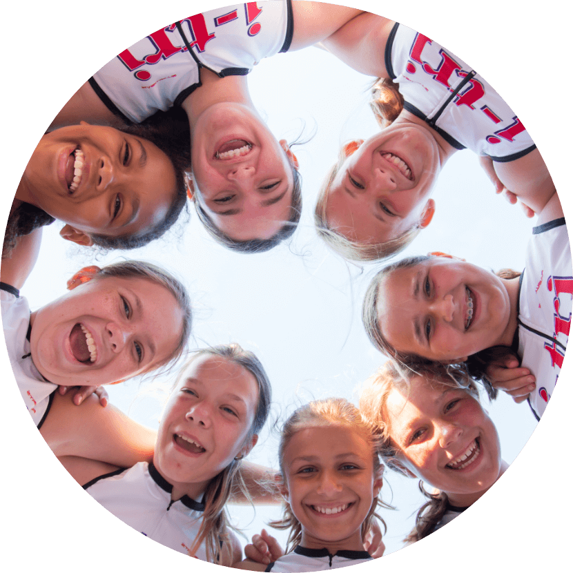 Camera looks up at a circle of 8 i-tri girls forming a ring with their heads and shoulders
