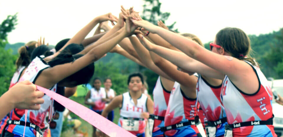 Runners link hands to form a bridge over a runner crossing the finish line
