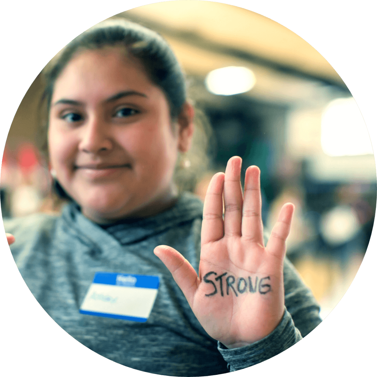 Girl holding up hand with 'Strong' written on it