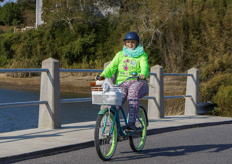 A cyclist rides across a bridge donning a Ride & Wine shirt.